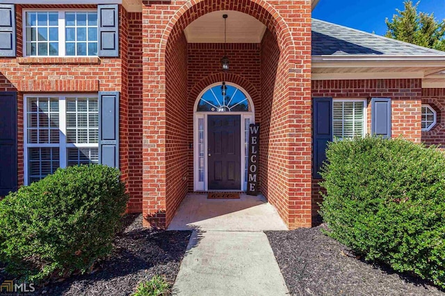 property entrance featuring brick siding and roof with shingles