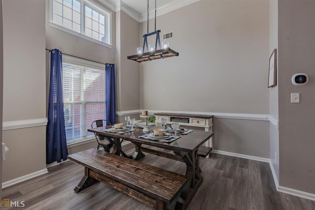 dining room featuring a notable chandelier, wood finished floors, visible vents, baseboards, and ornamental molding