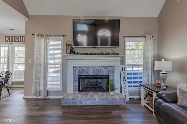 living area with visible vents, a fireplace, baseboards, and wood finished floors