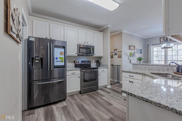 kitchen with white cabinets, crown molding, stainless steel appliances, and a sink