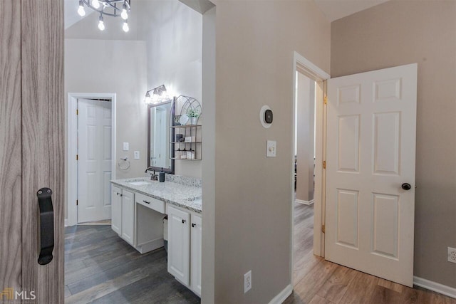 bathroom with wood finished floors, vanity, and baseboards