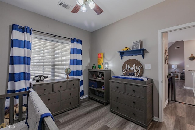 bedroom with ceiling fan, wood finished floors, visible vents, and baseboards