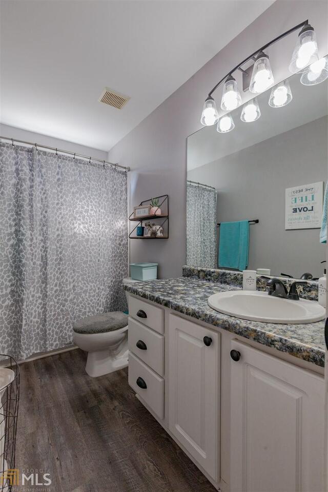 full bathroom featuring visible vents, vanity, toilet, and wood finished floors