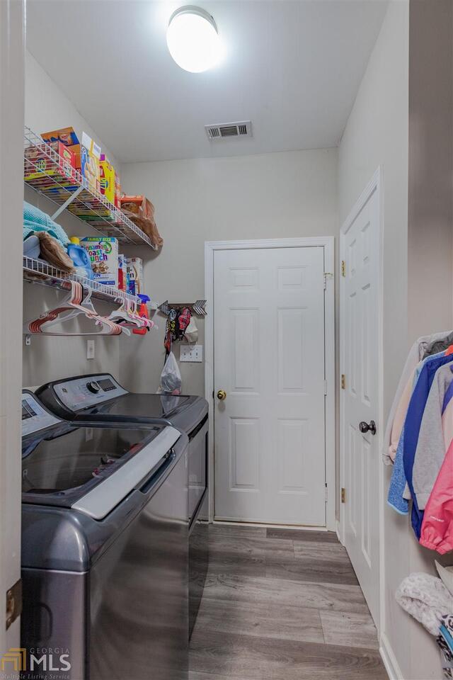 laundry room with laundry area, washer and clothes dryer, wood finished floors, and visible vents