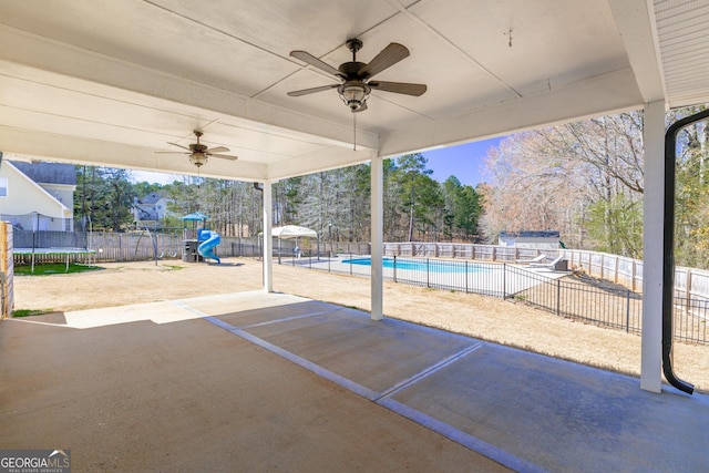 view of patio featuring a trampoline, a fenced in pool, playground community, and a fenced backyard