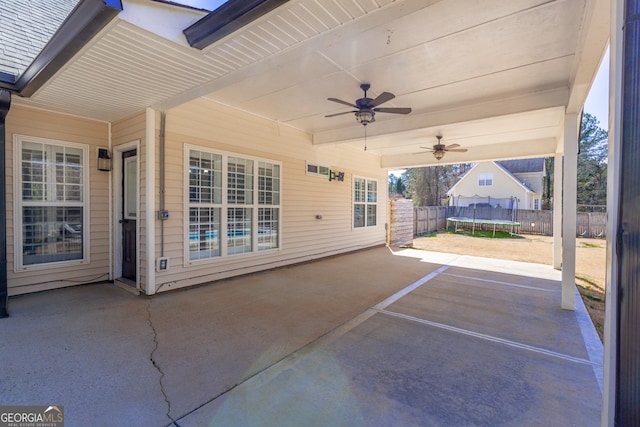 view of patio featuring ceiling fan, a trampoline, and a fenced backyard