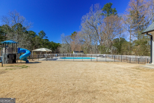 exterior space featuring a swimming pool, playground community, a lawn, and fence