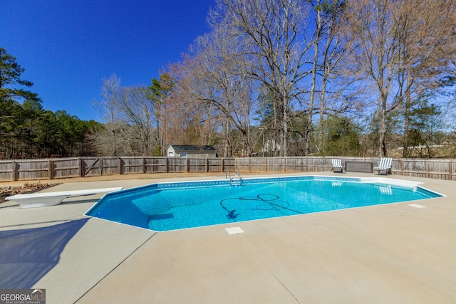 view of swimming pool featuring a fenced in pool, a fenced backyard, a patio, and a diving board