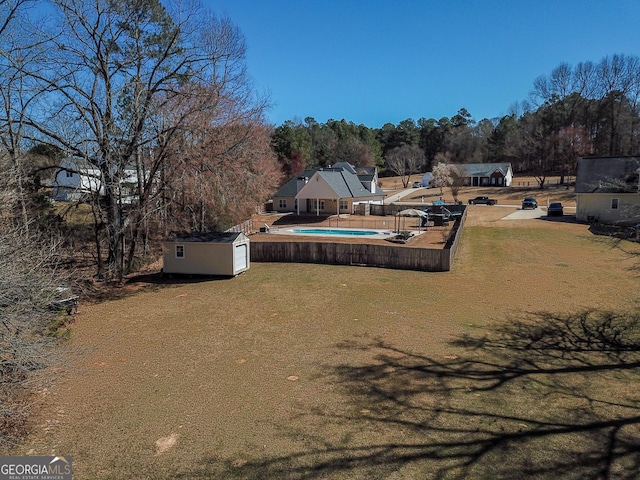 view of yard featuring a storage unit, a pool, and an outbuilding