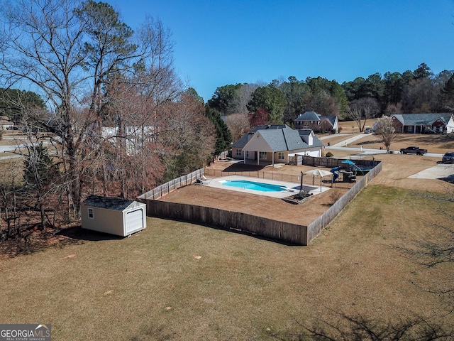 view of swimming pool featuring an outbuilding, a fenced backyard, a yard, and a shed