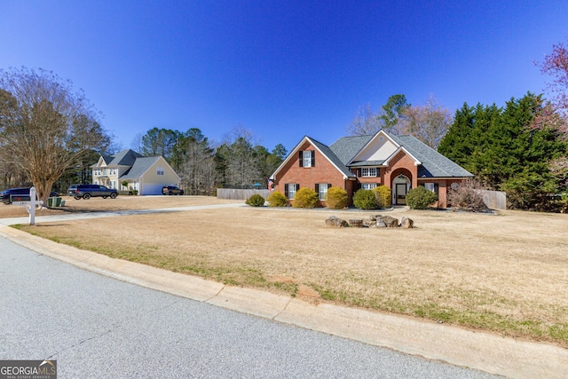 view of front of home featuring a front lawn, fence, and brick siding