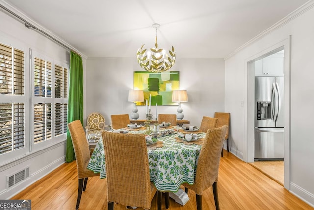 dining space featuring visible vents, baseboards, wood finished floors, an inviting chandelier, and crown molding