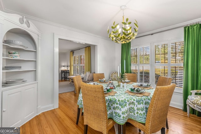 dining room featuring light wood-type flooring, crown molding, and an inviting chandelier