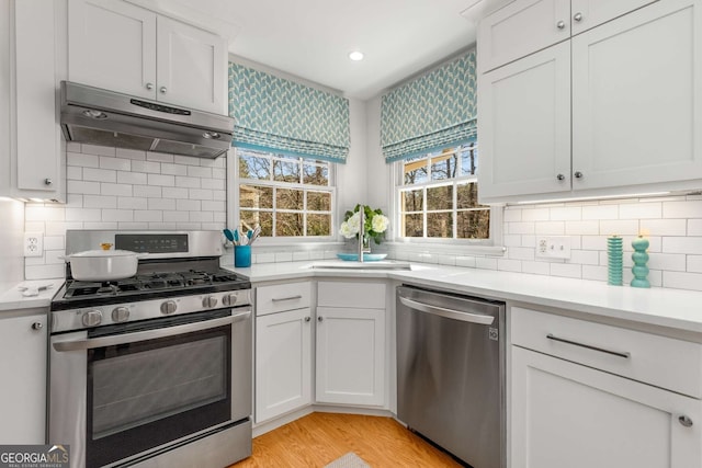 kitchen featuring under cabinet range hood, white cabinetry, appliances with stainless steel finishes, and light countertops