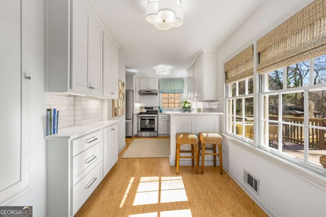 kitchen featuring visible vents, light wood-style flooring, appliances with stainless steel finishes, light countertops, and under cabinet range hood