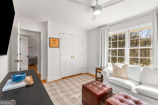 living room featuring light wood-type flooring, ceiling fan, and baseboards