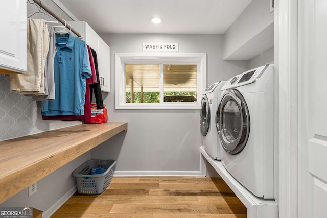 clothes washing area featuring recessed lighting, cabinet space, wood finished floors, washer and dryer, and baseboards