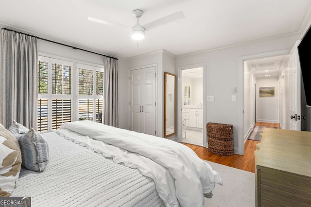 bedroom with ensuite bath, wood finished floors, a ceiling fan, and crown molding