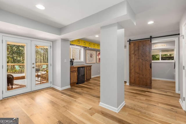 interior space featuring light wood finished floors, a barn door, baseboards, french doors, and recessed lighting