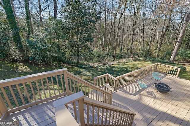 wooden terrace featuring a forest view, an outdoor fire pit, and a yard