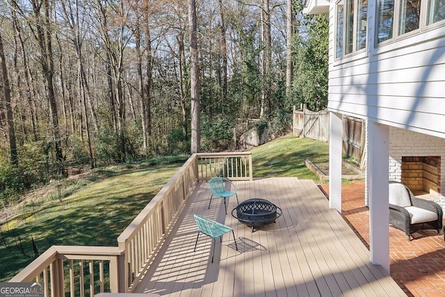 wooden deck featuring an outdoor fire pit and a lawn