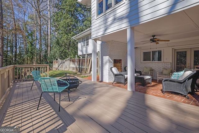 wooden deck featuring an outdoor living space with a fire pit, fence, and ceiling fan