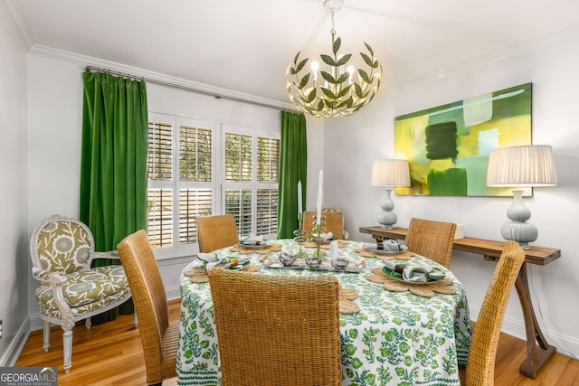 dining space with ornamental molding, wood finished floors, baseboards, and an inviting chandelier