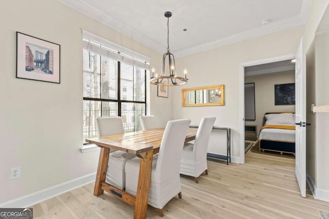 dining area featuring a notable chandelier, light wood-style flooring, baseboards, and crown molding