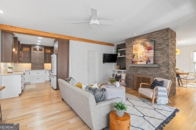 living area featuring recessed lighting, light wood-style floors, ceiling fan, and a stone fireplace