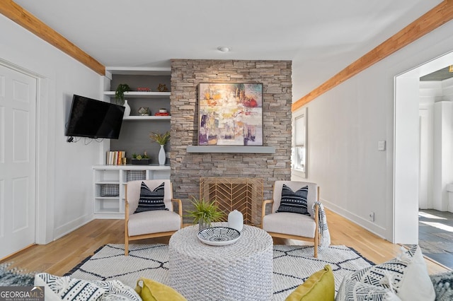 sitting room with a fireplace, wood finished floors, and baseboards