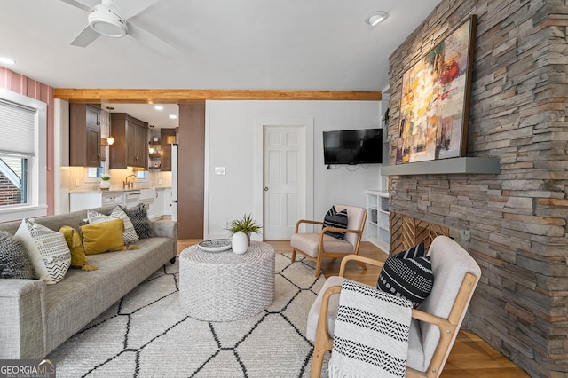 living room featuring light wood-style floors, ceiling fan, and a fireplace