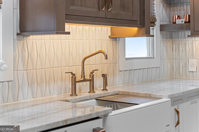 kitchen featuring light stone countertops, tasteful backsplash, and a sink