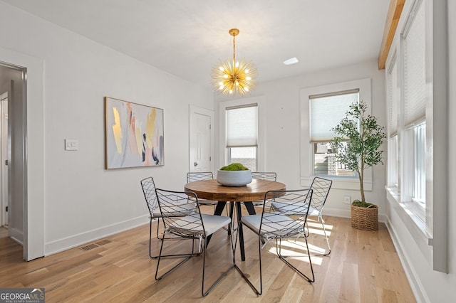 dining space featuring light wood-style floors, a notable chandelier, and baseboards