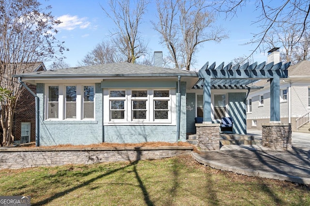 exterior space with a chimney, a pergola, and brick siding