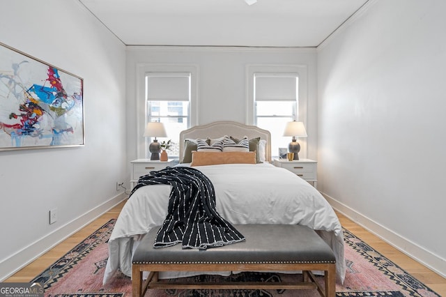 bedroom featuring crown molding, light wood finished floors, and baseboards