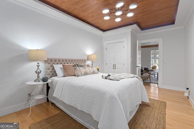 bedroom with a tray ceiling, wooden ceiling, wood finished floors, and crown molding