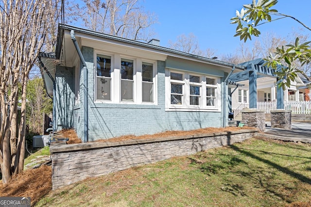 view of side of home with brick siding, a yard, and a pergola