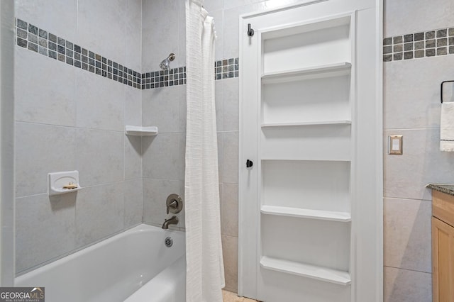 full bath featuring tile walls, shower / bathtub combination with curtain, and vanity