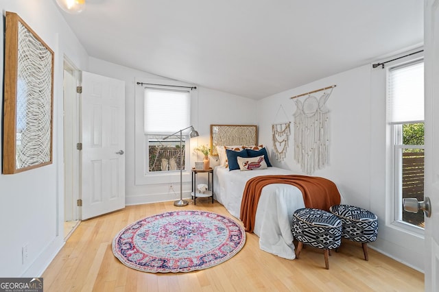 bedroom with multiple windows, vaulted ceiling, and wood finished floors