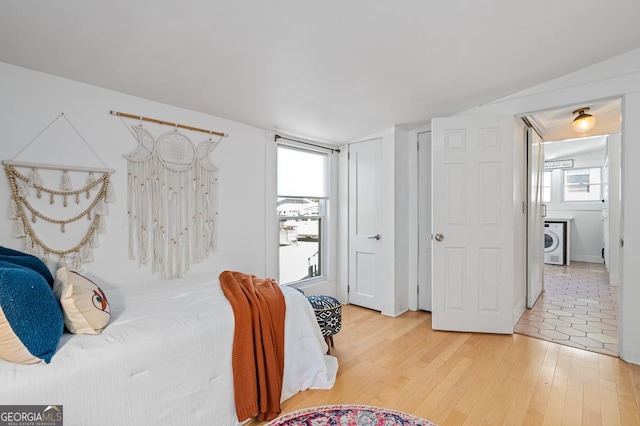 bedroom with light wood finished floors and washer / clothes dryer