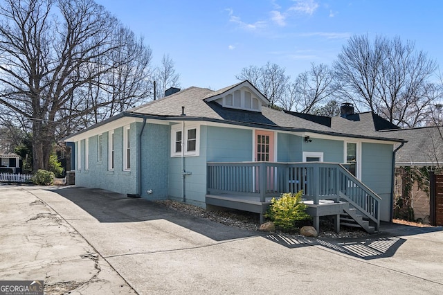 bungalow with a chimney, fence, and concrete driveway