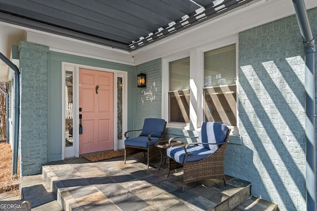 view of exterior entry with a porch and brick siding