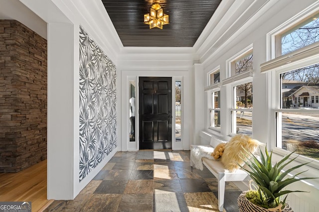 entrance foyer featuring plenty of natural light, a raised ceiling, and stone tile flooring