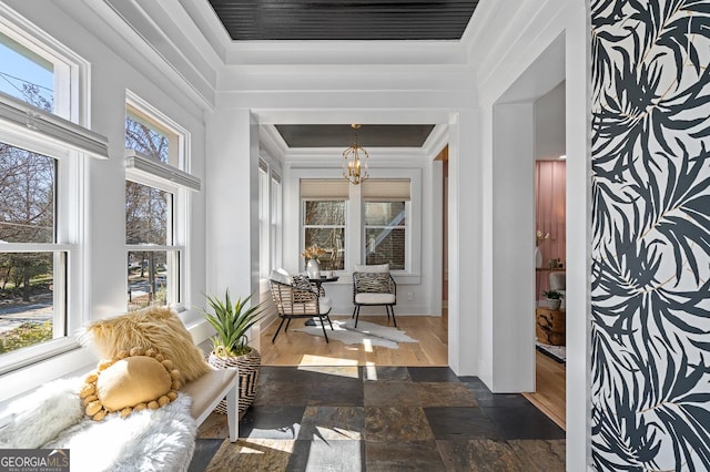 interior space with ornamental molding, stone tile flooring, and a notable chandelier