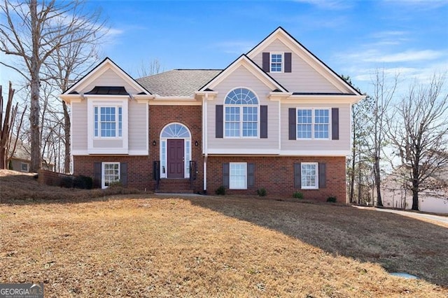 raised ranch with a front yard and brick siding