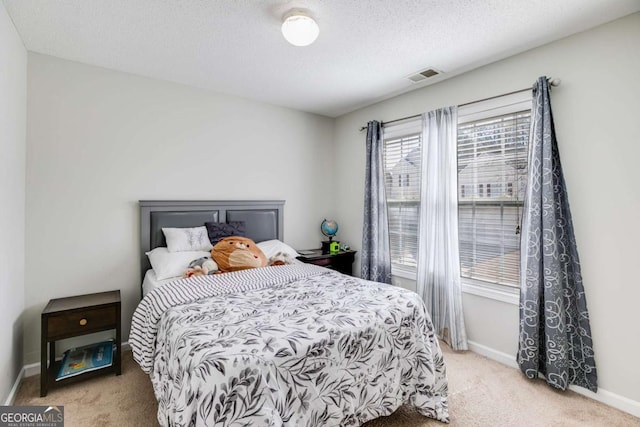 carpeted bedroom featuring a textured ceiling, visible vents, and baseboards