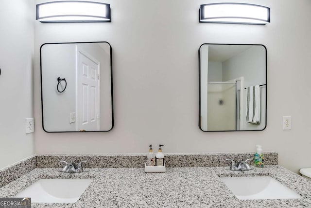 full bathroom with double vanity, a sink, and a shower with shower door