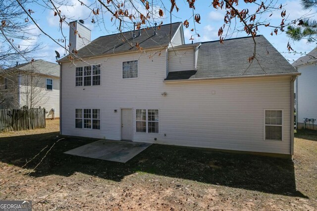 rear view of house with a patio, a chimney, and fence