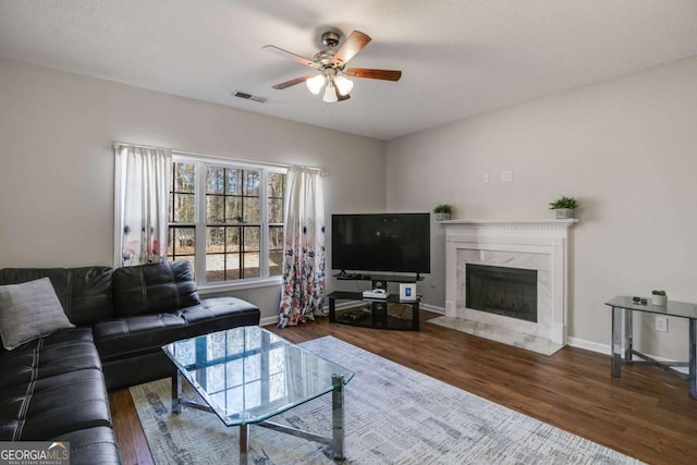 living area with visible vents, a premium fireplace, baseboards, and wood finished floors