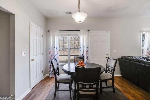 dining area with dark wood-style flooring, visible vents, and baseboards